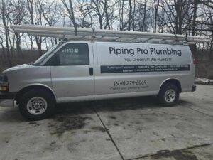 Piping Pro Plumbing service van with company branding, parked on a driveway, featuring a ladder rack and contact details for plumbing services.