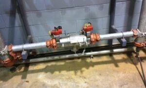 Industrial backflow prevention assembly installed in a commercial plumbing system, featuring a reduced pressure zone (RPZ) backflow preventer and shut-off valves to protect potable water from contamination.
