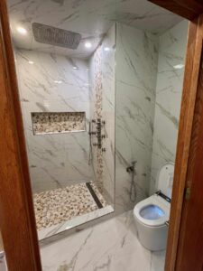 Commercial bathroom shower and toilet fixture installation with marble tile — Piping Pro Plumbing, Sun Prairie, WI