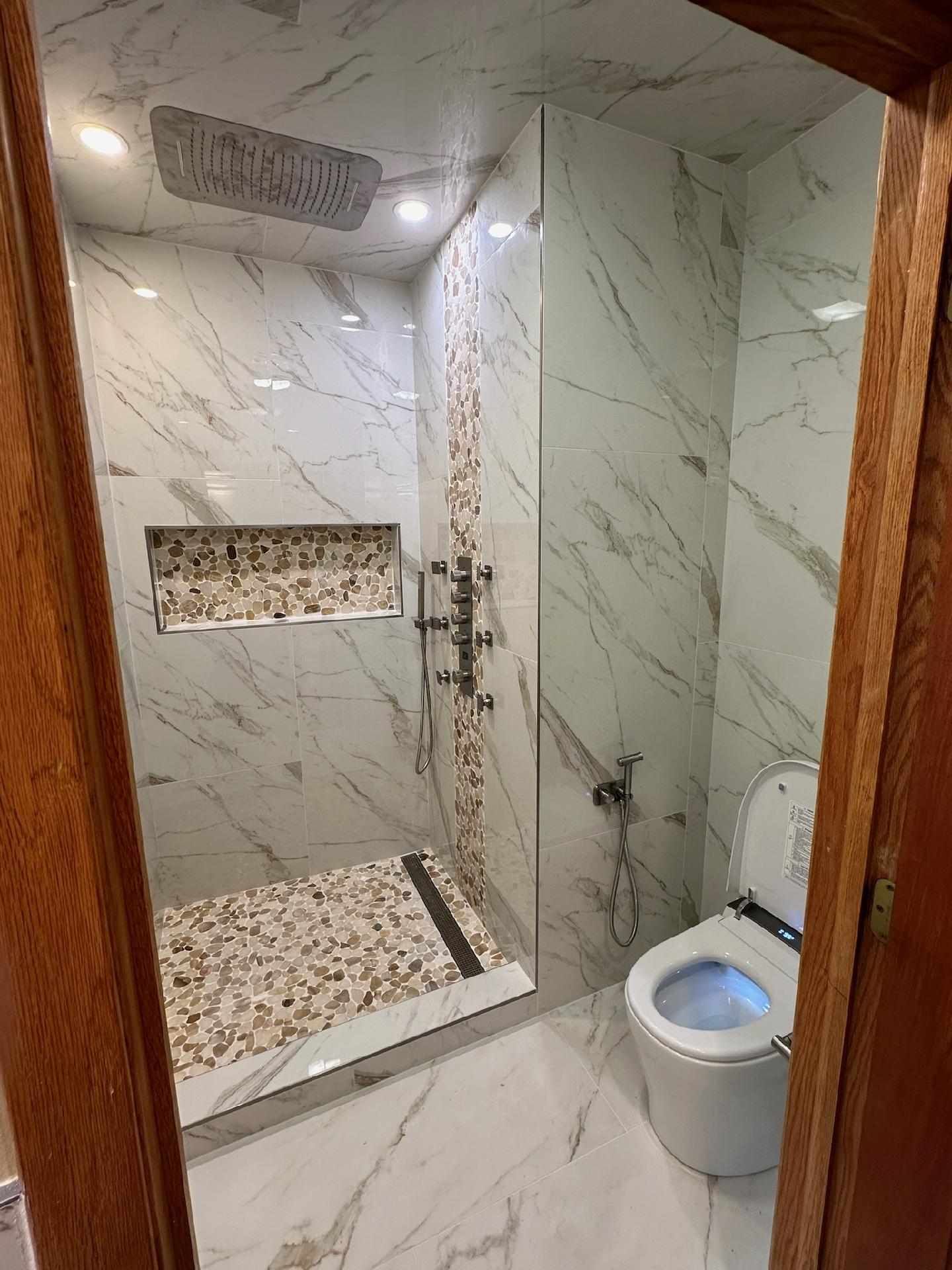 Commercial bathroom shower and toilet fixture installation with marble tile — Piping Pro Plumbing, Sun Prairie, WI